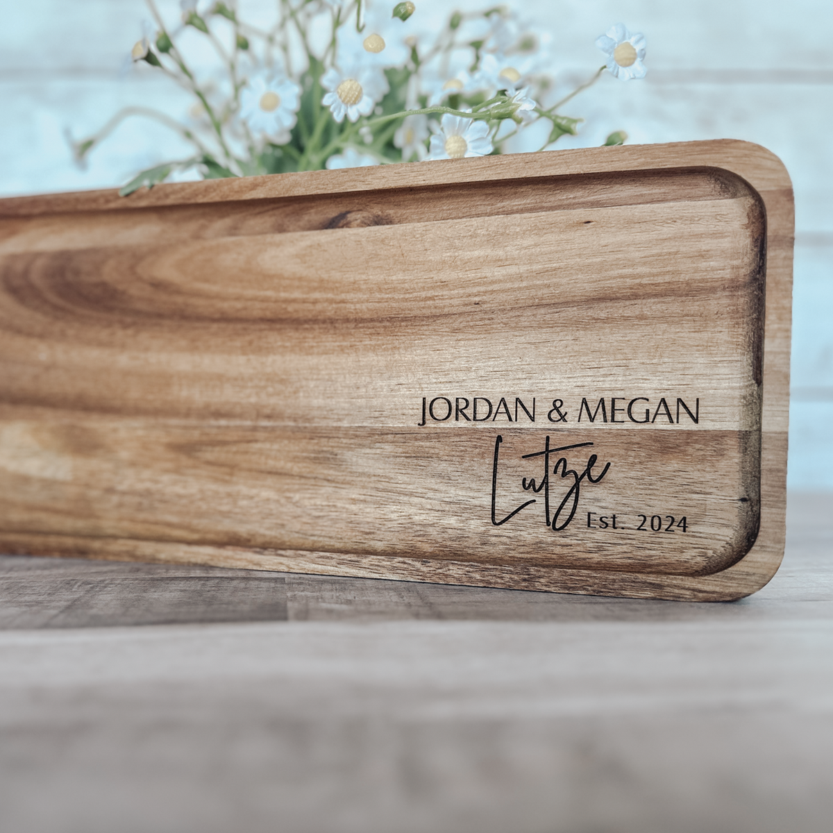 Personalized acacia wood serving tray with engraved couple's name and date, styled with fresh flowers